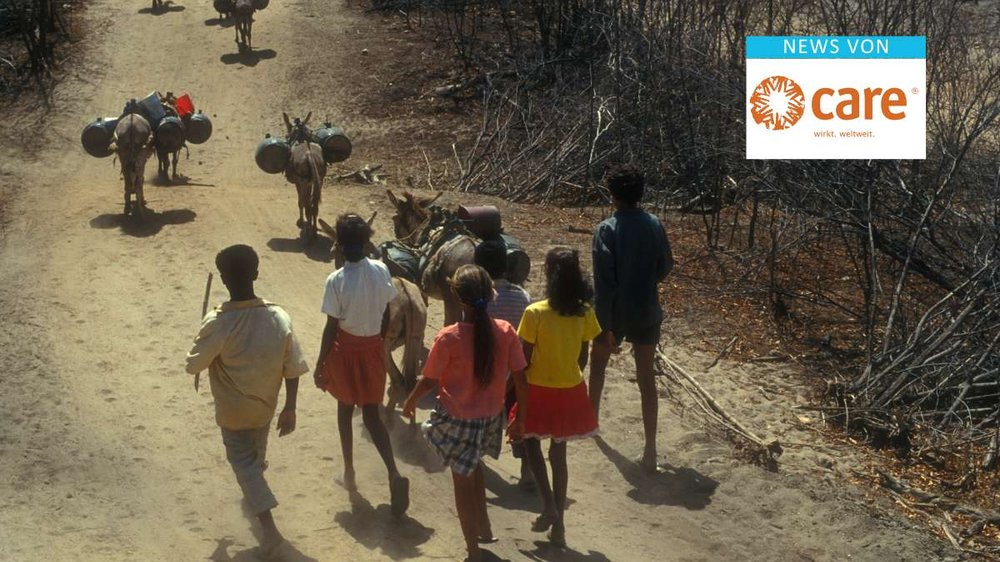 Dürre. Fünf Kinder und Jugendliche gehen eine ausgetrocknete Straße entlang, vor ihnen laufen einige bepackte Esel.